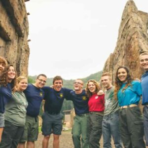 Photo of young adult group in front of cliff edges. They are wearing casual clothing and they are smiling