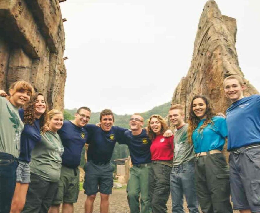 Photo of young adult group in front of cliff edges. They are wearing casual clothing and they are smiling